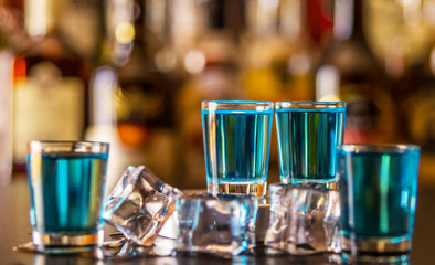 Popular blue drink shot kamikaze on the background of the bar with bottles, a refreshing drink