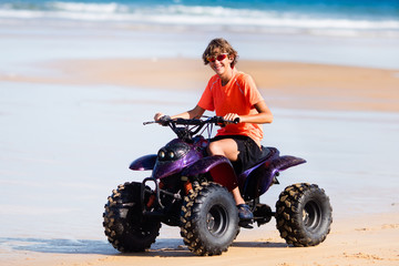 Teenager riding quad bike on beach