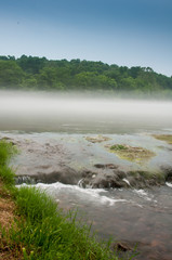 Water cascades from a misty river