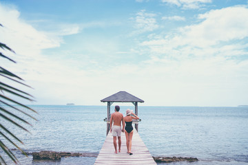 Honey moon on the sea shore. Back view of loving couple walking together on wooden pier.