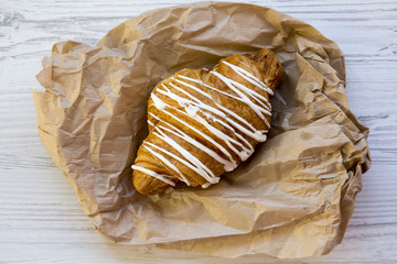 Freshly baked croissant on white wooden table, top view