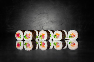 Sushi roll inari on black background made of Seaweed, marinated rice, cucumber, salad leaf, tuna, salmon, thai sause. Sushi menu. Japanese food. Free-space. Close-up.