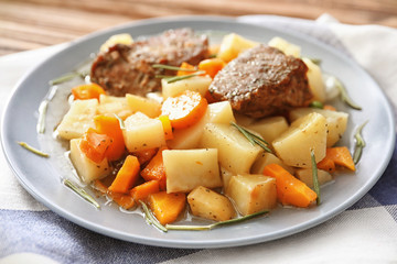 Plate with tasty meat and potatoes on table