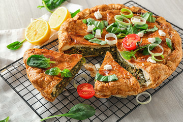 Tasty pie with spinach on cooling rack