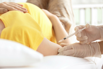 Doctor vaccinating pregnant woman in clinic