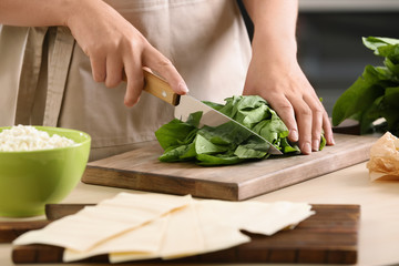Woman cooking spinach lasagna in kitchen
