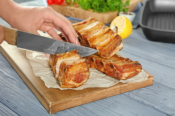 Woman cutting delicious ribs in kitchen