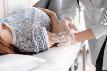 Doctor vaccinating pregnant woman in clinic