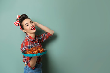 Funny young housewife with homemade pastry on color background