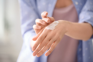 Young woman applying hand cream, closeup