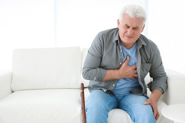 Senior man having heart attack on sofa