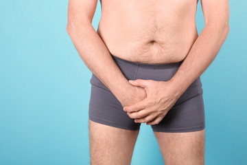 Mature man with urological problems suffering from pain on color background