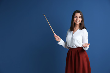 Portrait of female teacher with pointer on color background