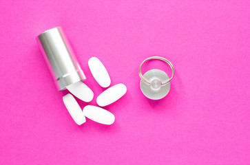 Metal container and pills on a pink background, close-up