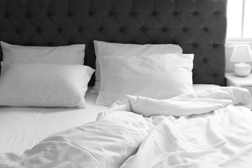 Comfortable bed with white linen and pillows at home