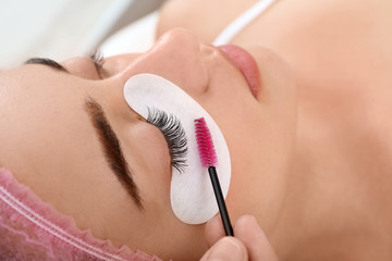 Obraz na płótnie Canvas Young woman undergoing eyelash extensions procedure, closeup