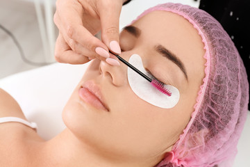 Naklejka premium Young woman undergoing eyelash extensions procedure, closeup