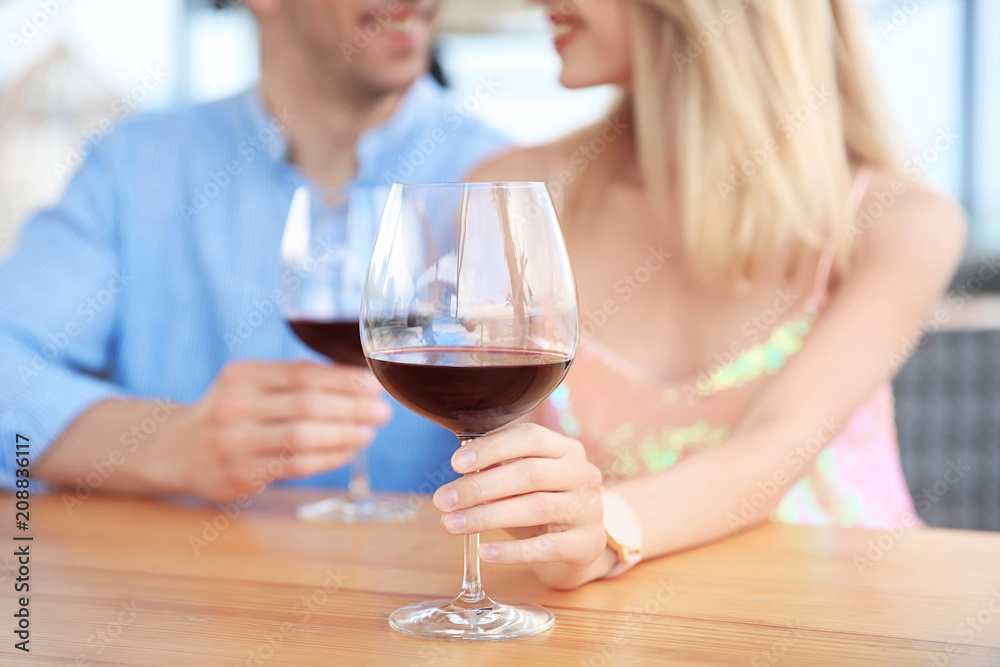 Poster young romantic couple with glasses of red wine at table