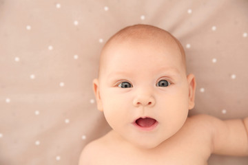 Adorable baby girl lying on bed, top view