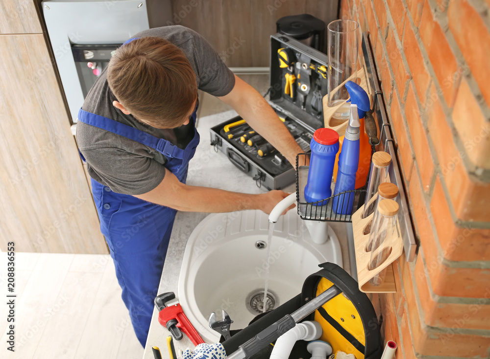 Sticker Professional plumber in uniform fixing kitchen sink