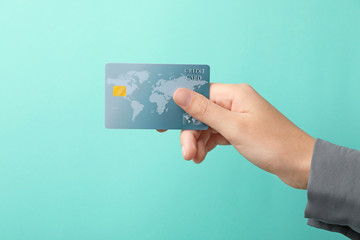 Woman holding credit card on color background