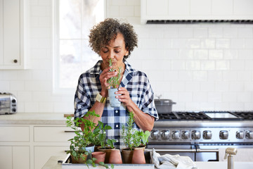 Senior African American woman smelling fresh herbs in her kitchen