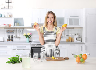 Young woman preparing lemonade on table in kitchen. Natural detox drink