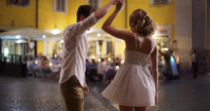 Happy carefree couple dancing on street in Italy, Caucasian male and female enjoying date night outdoors smiling, 4k