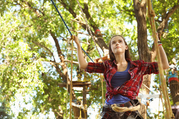 Teenage girl climbing in adventure park. Summer camp