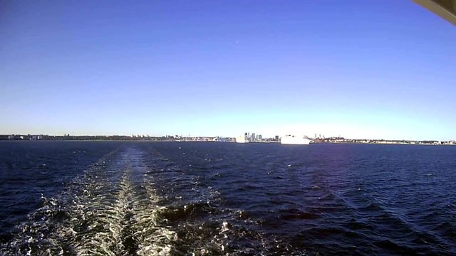 The farry ship leaves the port, leaving a trail on the water