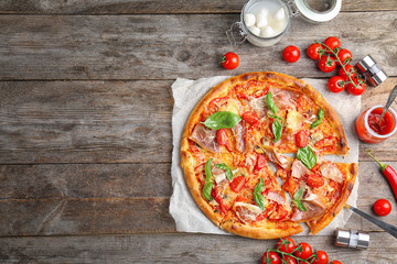 Delicious pizza with tomatoes and meat on wooden background