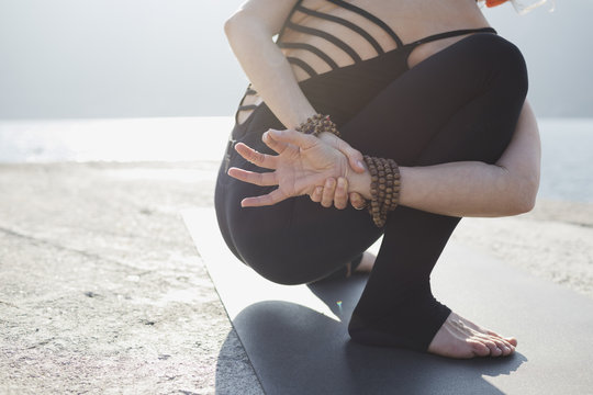 Woman doing Twisting Garland Pose, Bada Malasana
