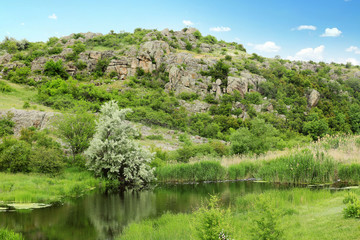 Beautiful landscape with beautiful pond and rocky hill. Camping season
