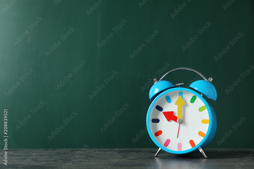 Poster Alarm clock on table against color background. Time concept