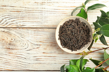 Plate with dry tea and fresh green leaves on table, top view