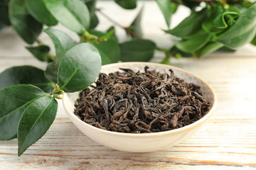 Plate with dry tea and fresh plant on table