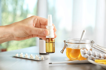 Woman holding remedy for cold over table