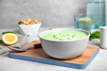 Green pea soup in bowl on wooden board