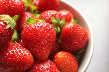 Bowl with ripe strawberries on grey background, closeup