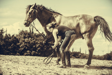 Jockey woman taking care of horse