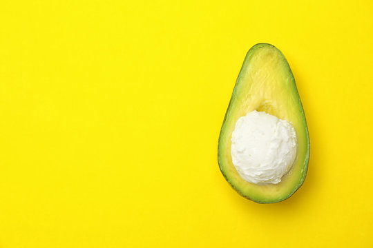 Composition with ripe avocado and ice cream on color background, top view
