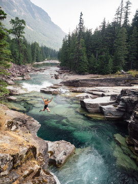 Young woman in black bathing suit diving into frigid and cold river in Montana.