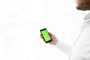 Close-up of male hands using smartphone near the window. Close up. Tracking motion. Vertical. pants.