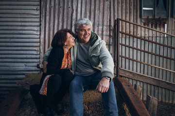 A married senior couple together sitting in a rustic rural setting