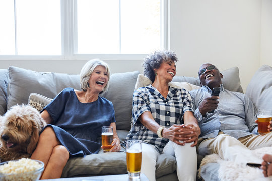 Multiethnic seniors drinking, socializing and watching TV together at home