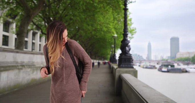 Woman walking by the River Thames using her cellphone, Attractive female using map on smartphone, 4k