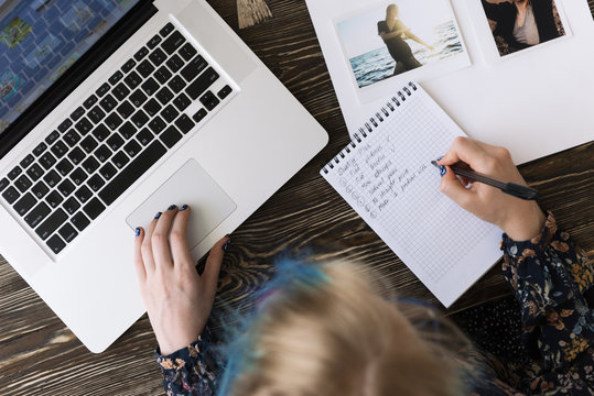 A person writing sitting at laptop
