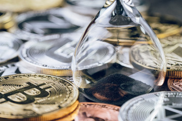 Time countdown for crypto currency price, sandglass or hourglass with various of shiny silver and golden physical cryptocurrencies symbol coins including Bitcoin