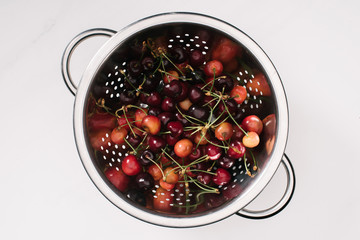 top view of fresh ripe sweet healthy cherries in colander isolated on white