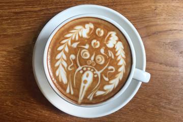 view from above of delicious cup of Italian coffee latte with amazing milk foam artistic decoration of hindi god at table of working desk or coffee shop